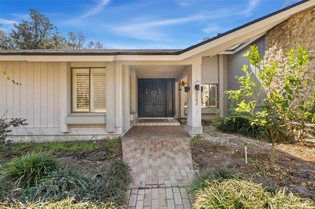 A brick walkway leads to the double front doors of a house with stone siding — 2345 NW 14TH PLACE, GAINESVILLE, FL