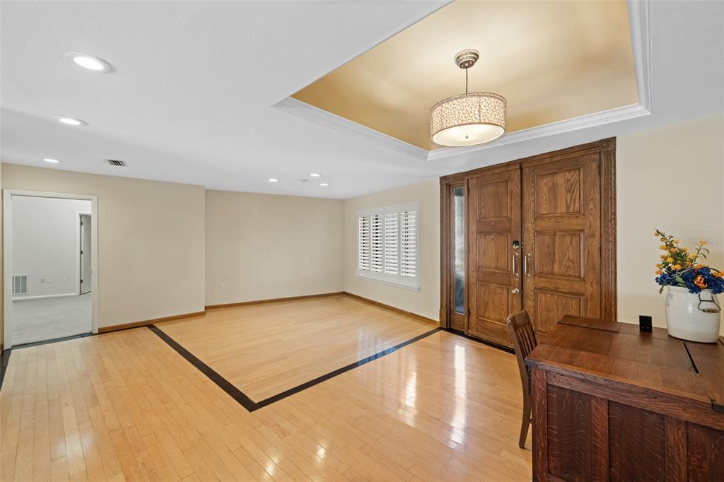 A foyer features light wood flooring with a dark border, double doors, and a tray ceiling — 2345 NW 14TH PLACE, GAINESVILLE, FL