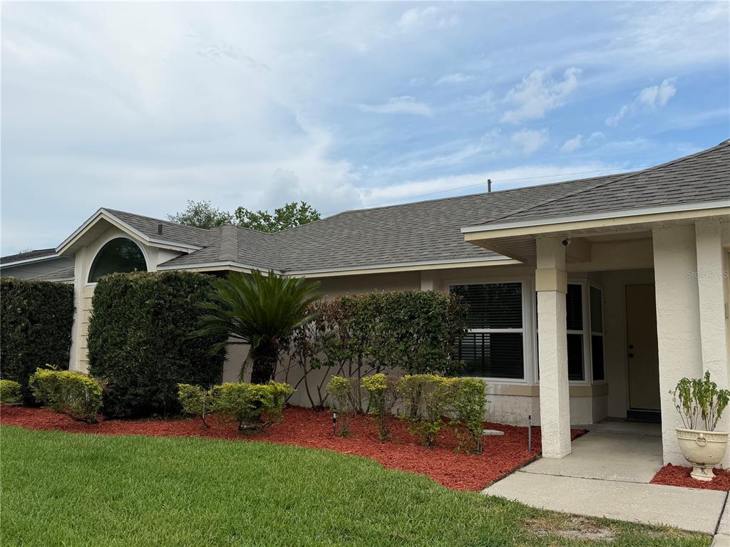 A single-story house exterior features a beige stucco facade, a shingled roof, and landscaped bushes — 3727 DUNWICH AVENUE, ORLANDO, FL