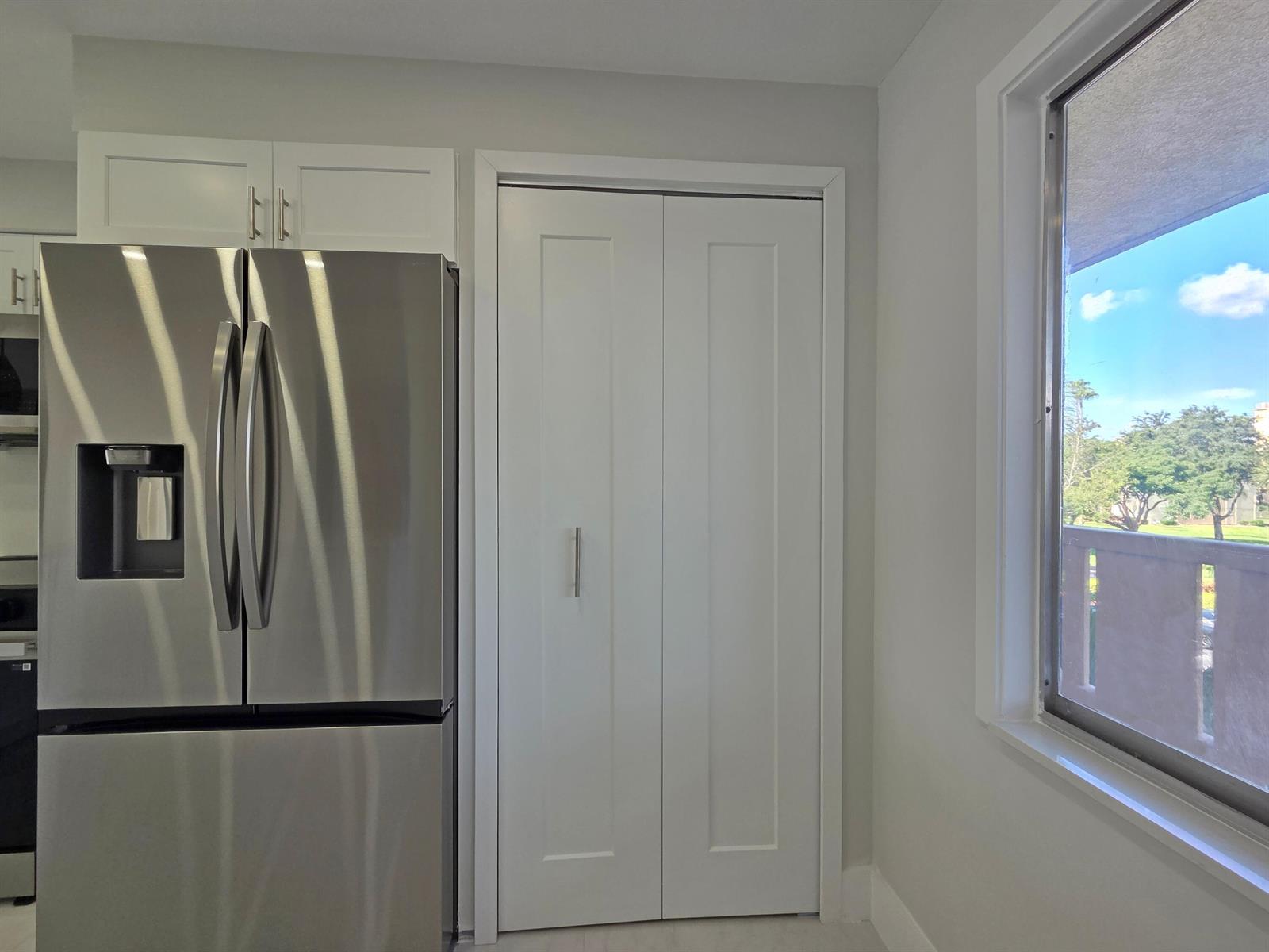 A stainless steel refrigerator stands next to a white closet door and a window — 14310 Strathmore Lane # 305, Delray Beach FL 33446, DELRAY BEACH, FL