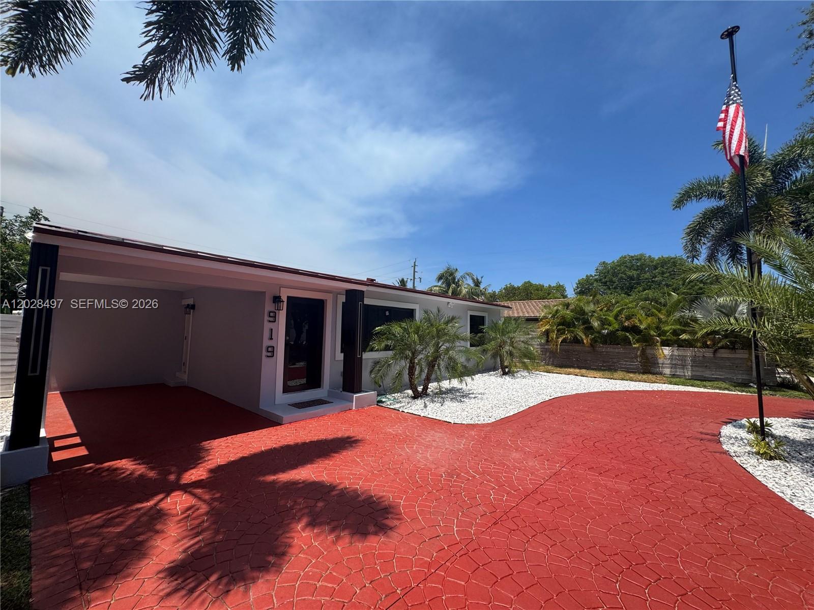 A single-story house features a red stamped concrete driveway, a carport, and a flag pole — 919 NE 4th Ct, Hallandale Beach FL 33009, HALLANDALE BEACH, FL