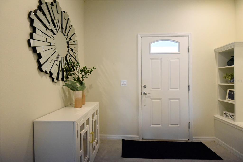 An entryway features a white console table, a sunburst mirror, and a white front door — 8942 SYDNEY AVENUE, KISSIMMEE, FL