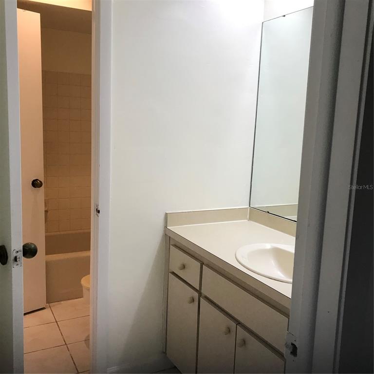 A bathroom features a vanity with a white countertop and a separate tiled shower area — 13610 S VILLAGE DRIVE UNIT 4103, TAMPA, FL