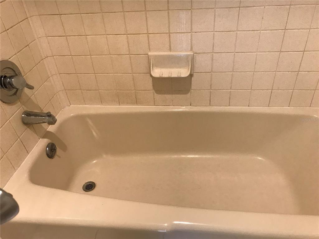 A beige bathtub with a matching soap dish is surrounded by square wall tiles — 13610 S VILLAGE DRIVE UNIT 4103, TAMPA, FL