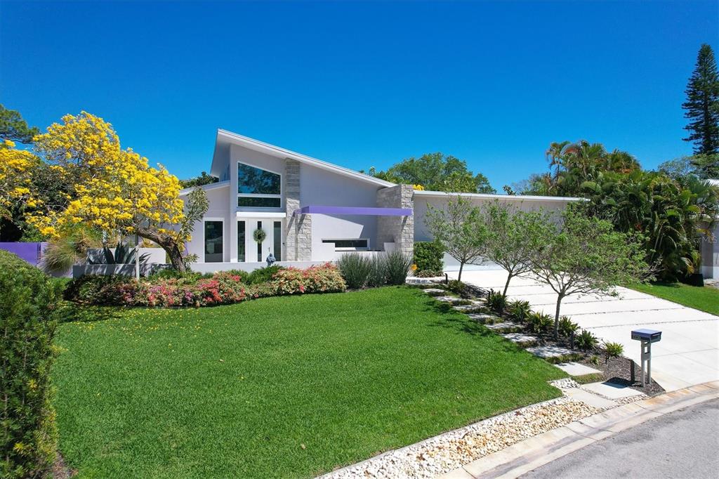 A modern house with a slanted roof, stone accents, and a purple entryway overhang — 1556 EASTBROOK DRIVE, SARASOTA, FL