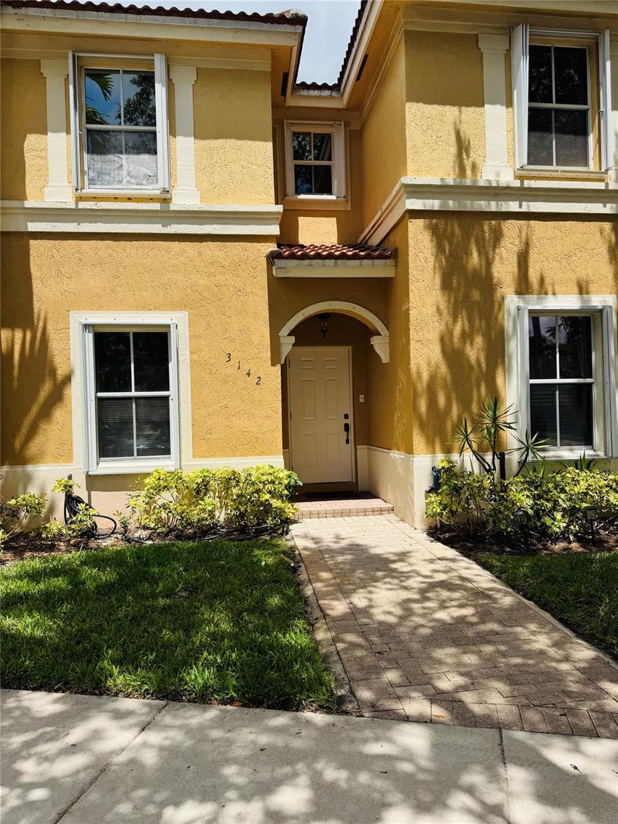 A two-story yellow stucco house with a paved walkway leading to the front entrance — 3142 SW 129th Way # 156, Miramar FL 33027, MIRAMAR, FL