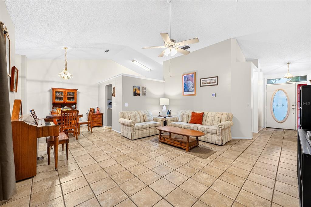 A living room and dining area with vaulted ceilings, tile floors, and a ceiling fan — 1464 CRAWFORD DRIVE, APOPKA, FL