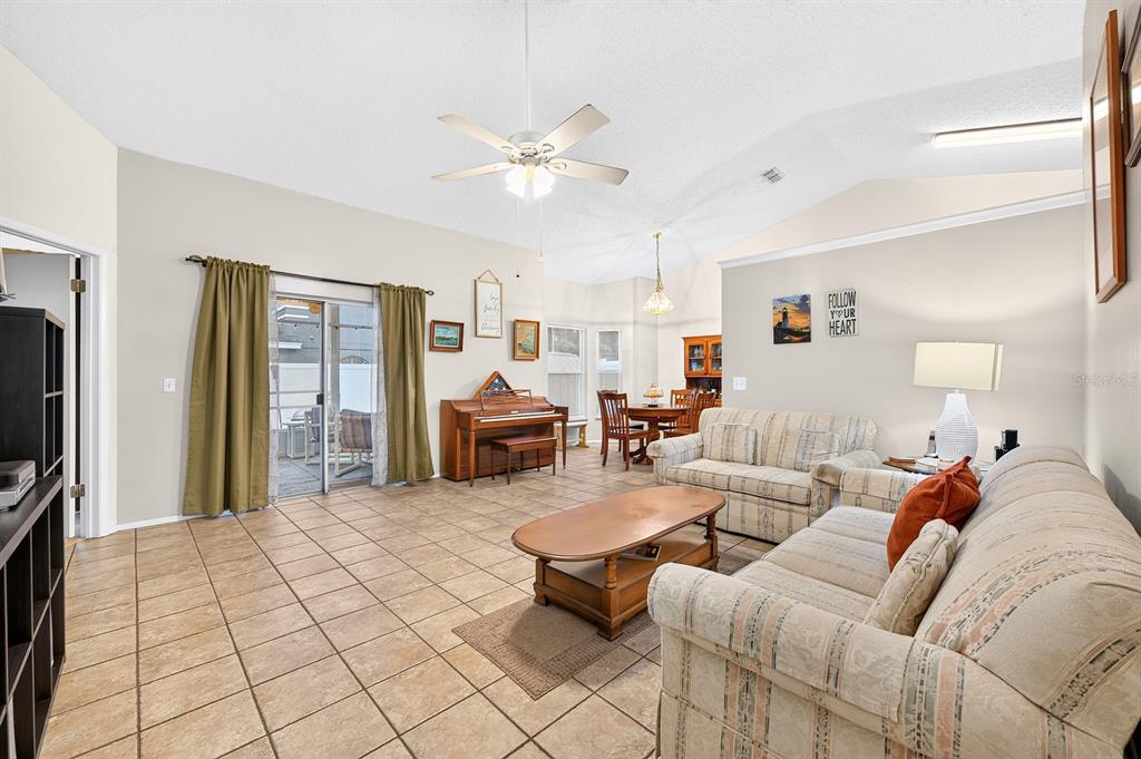 A living room with tile floors, a vaulted ceiling, a piano, and beige upholstered furniture — 1464 CRAWFORD DRIVE, APOPKA, FL