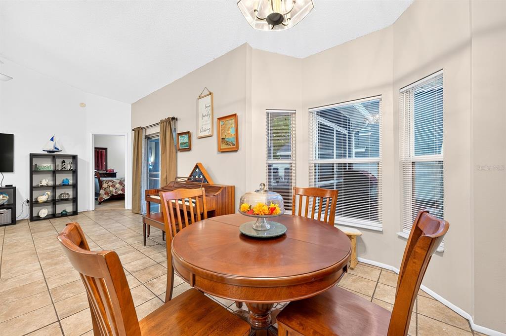 A dining area features a round wooden table, four chairs, and a bay window — 1464 CRAWFORD DRIVE, APOPKA, FL