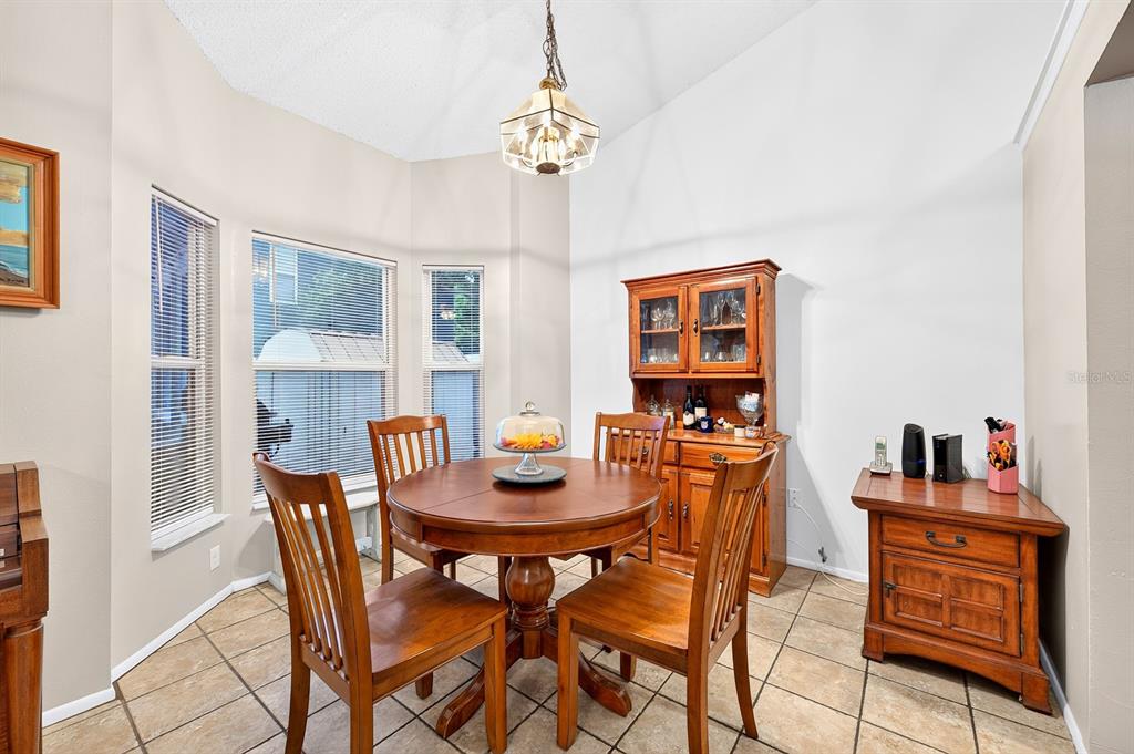 A dining room with a round wooden table, chairs, a hutch, and tile flooring — 1464 CRAWFORD DRIVE, APOPKA, FL