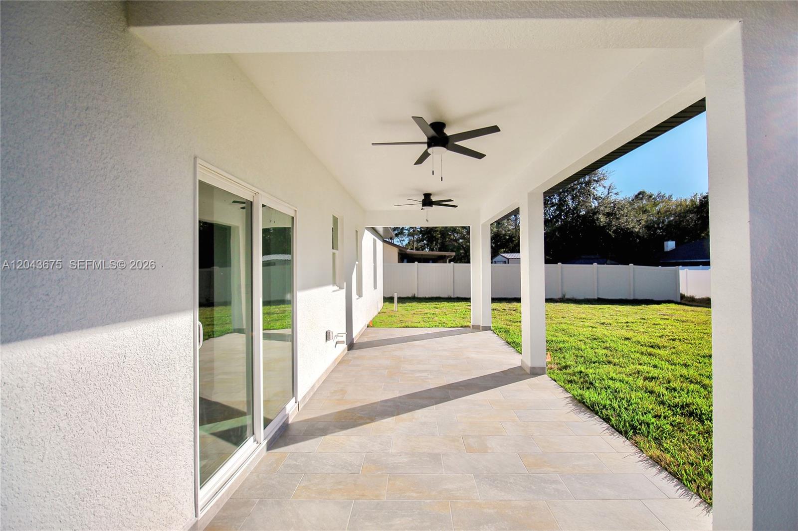 A covered patio features tiled flooring, two ceiling fans, and a view of the backyard — 3915 EL RADO AVE, Sebring FL 33872, SEBRING, FL