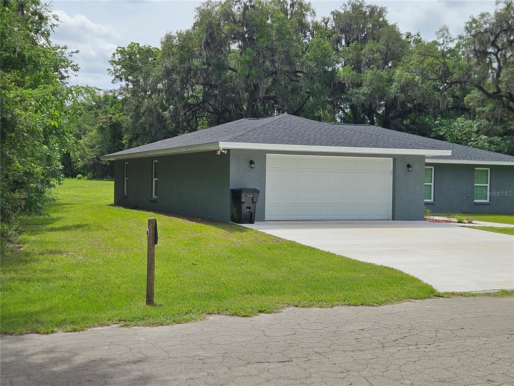 A gray single-story house features a two-car garage and a large, grassy side yard — 51 NE 10TH STREET, WILLISTON, FL