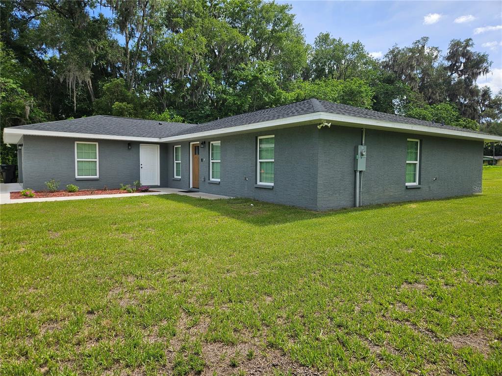 A gray, single-story ranch-style house with a dark roof and white-trimmed windows — 51 NE 10TH STREET, WILLISTON, FL