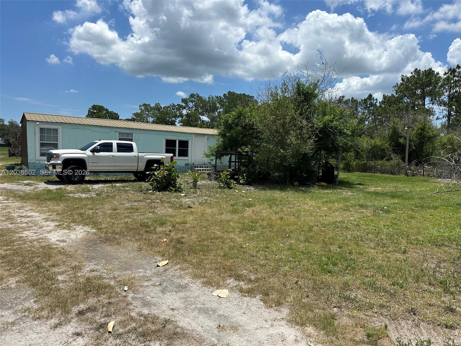 A white pickup truck is parked in front of a light blue mobile home — 135 S Hacienda, Clewiston FL 33440, CLEWISTON, FL
