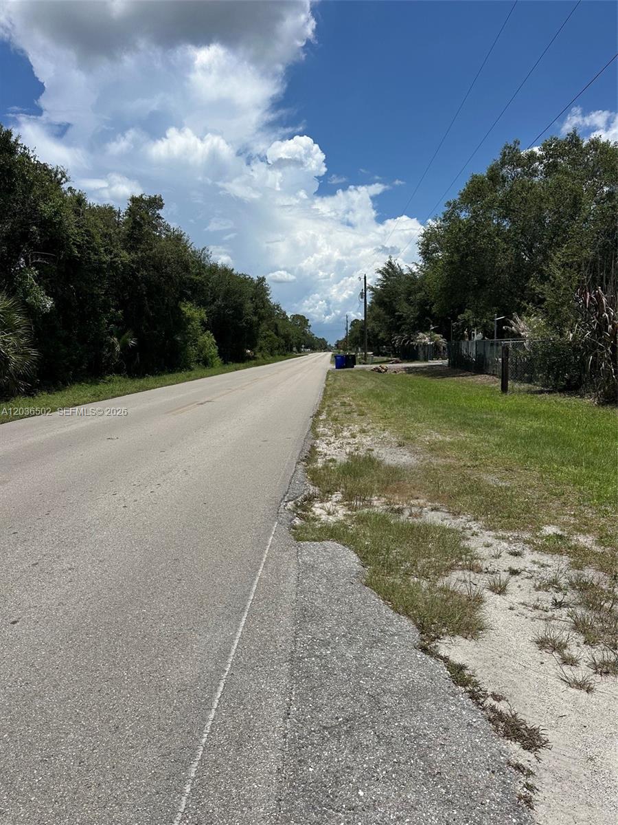 A paved road stretches into the distance, flanked by trees and a grassy shoulder — 135 S Hacienda, Clewiston FL 33440, CLEWISTON, FL