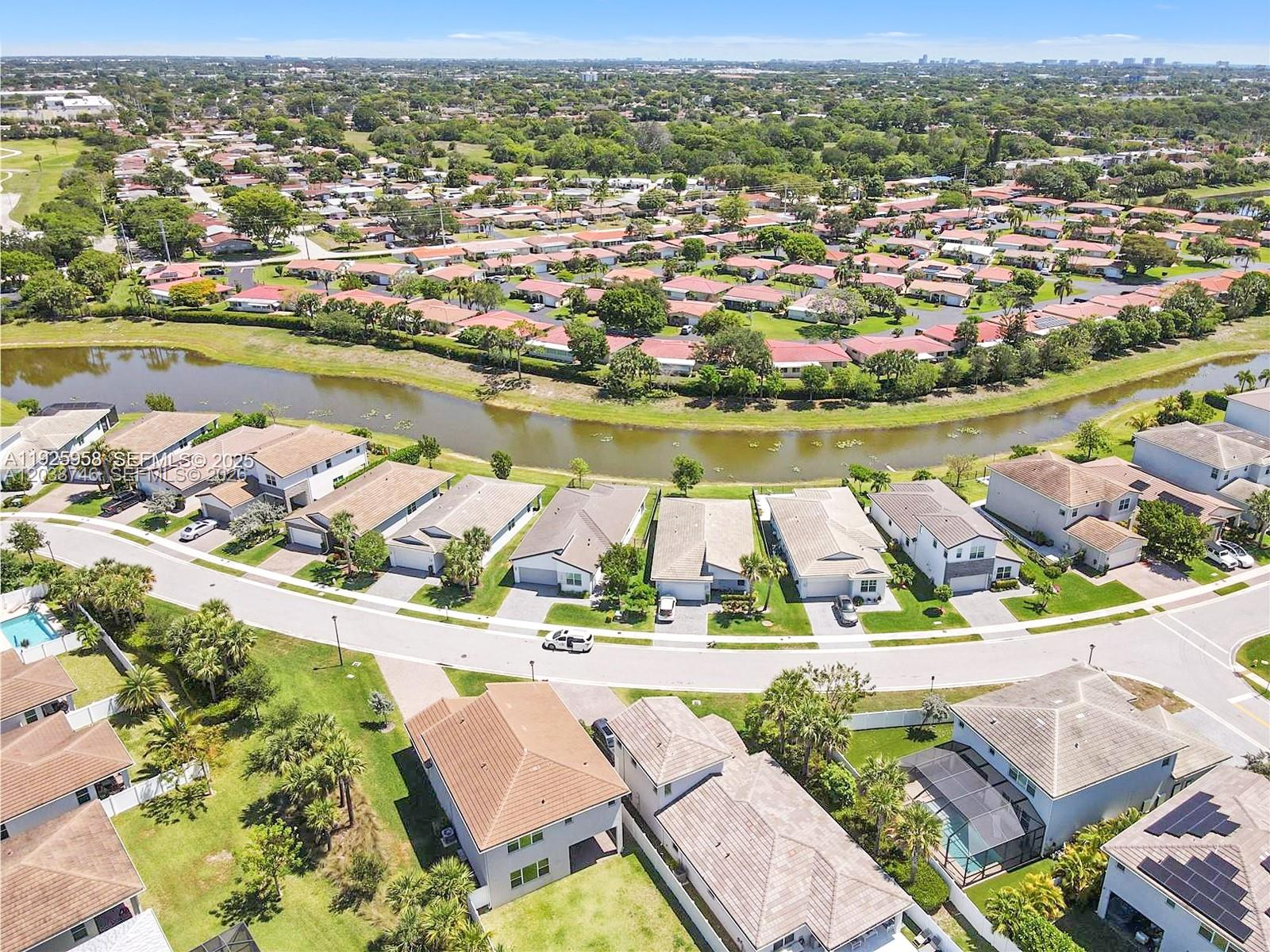 An aerial view shows suburban houses with tiled roofs situated along a winding canal — 4242 Rosa Dr, Deerfield Beach FL 33064, DEERFIELD BEACH, FL