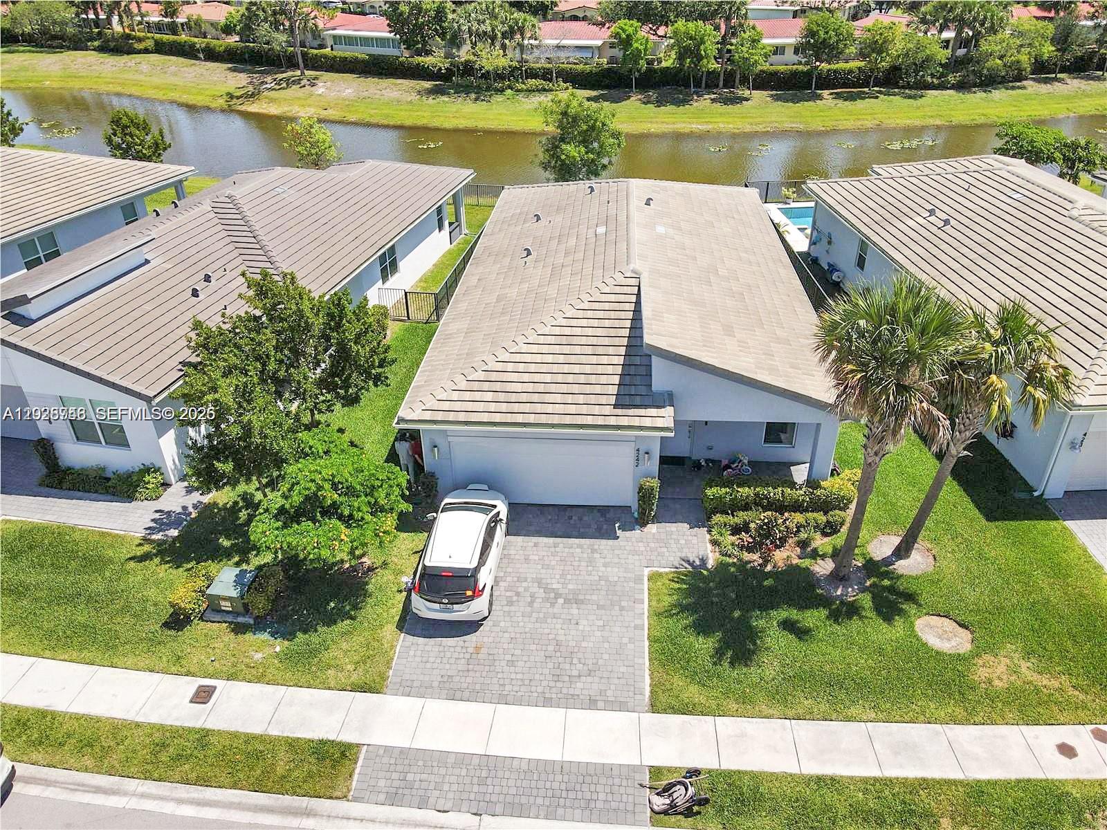 An aerial view shows a suburban house with a tiled roof, driveway, and backyard pool — 4242 Rosa Dr, Deerfield Beach FL 33064, DEERFIELD BEACH, FL