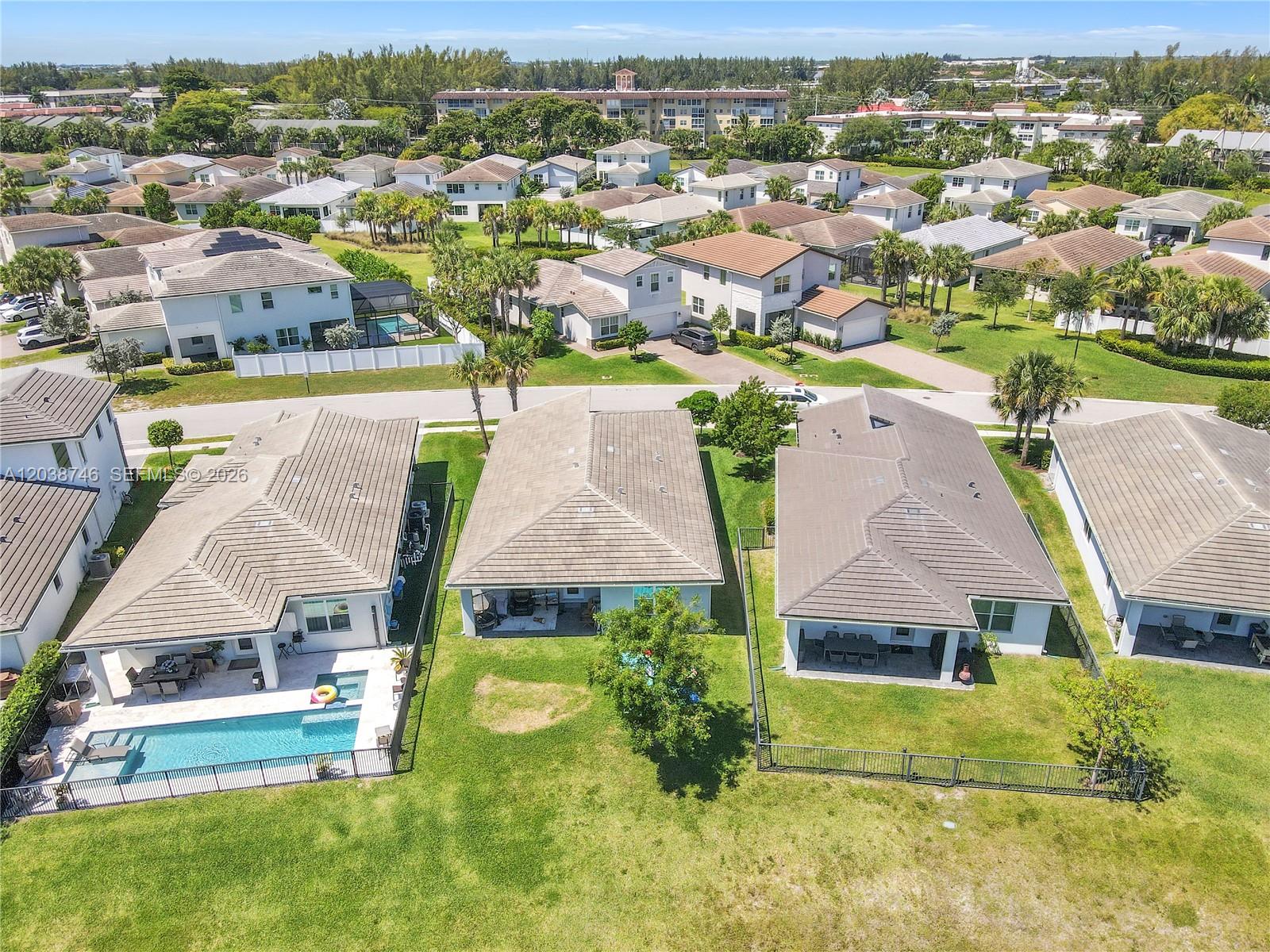 An aerial view shows several suburban houses with tiled roofs and fenced backyards — 4242 Rosa Dr, Deerfield Beach FL 33064, DEERFIELD BEACH, FL