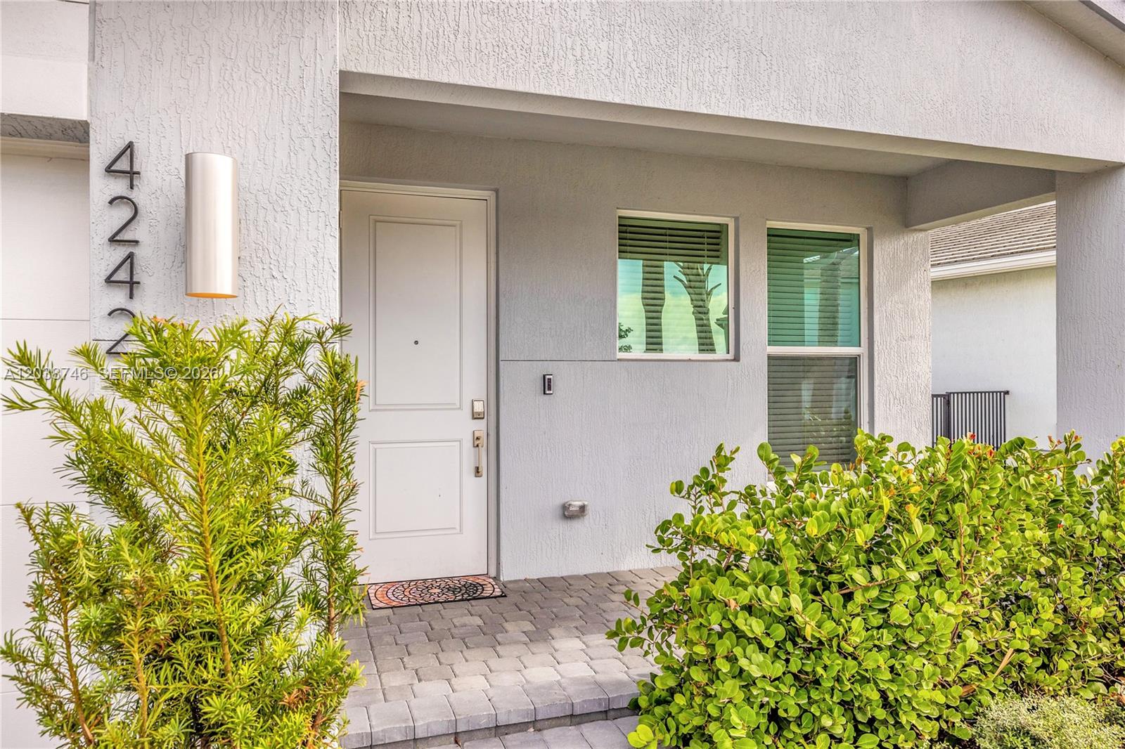 A modern home entrance features a white door, house numbers, and a paved porch — 4242 Rosa Dr, Deerfield Beach FL 33064, DEERFIELD BEACH, FL