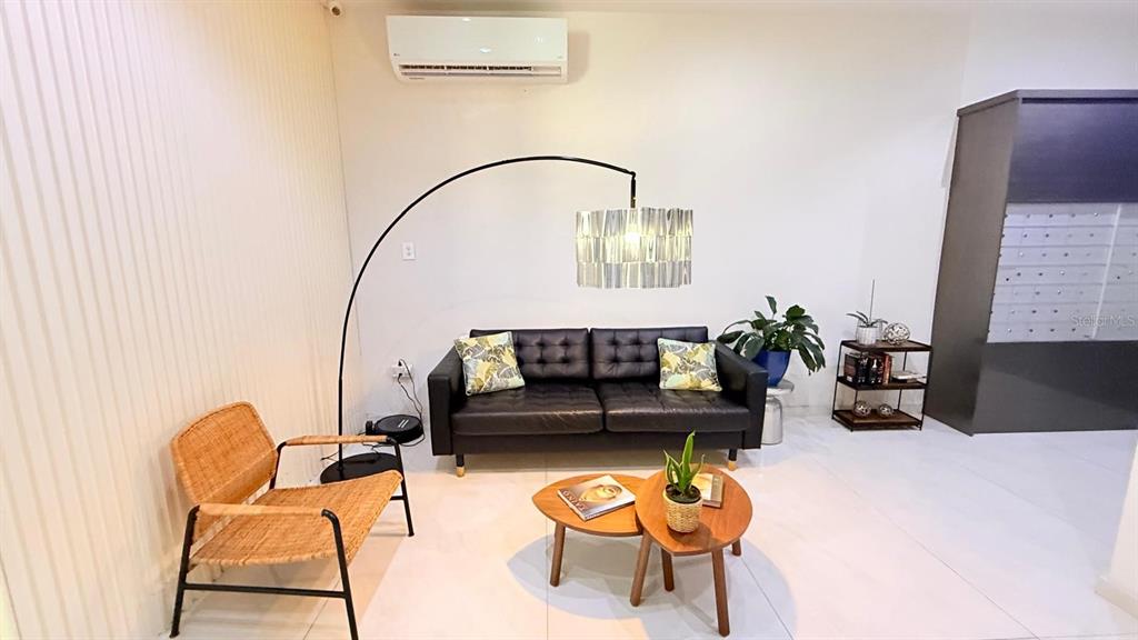 A living room features a black leather sofa, a wicker chair, and two wooden coffee tables — 37 ISLA VERDE AVE. UNIT 203, CAROLINA, PR