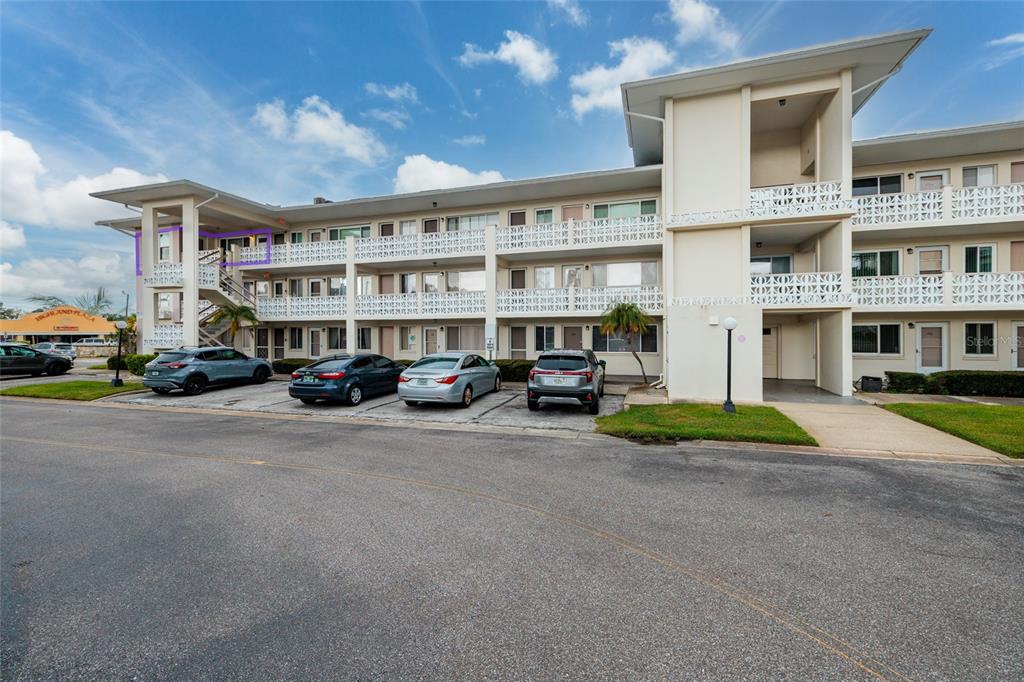 An exterior view of a multi-story apartment building with a parking lot in front — 1235 S HIGHLAND AVENUE UNIT 2-301, CLEARWATER, FL