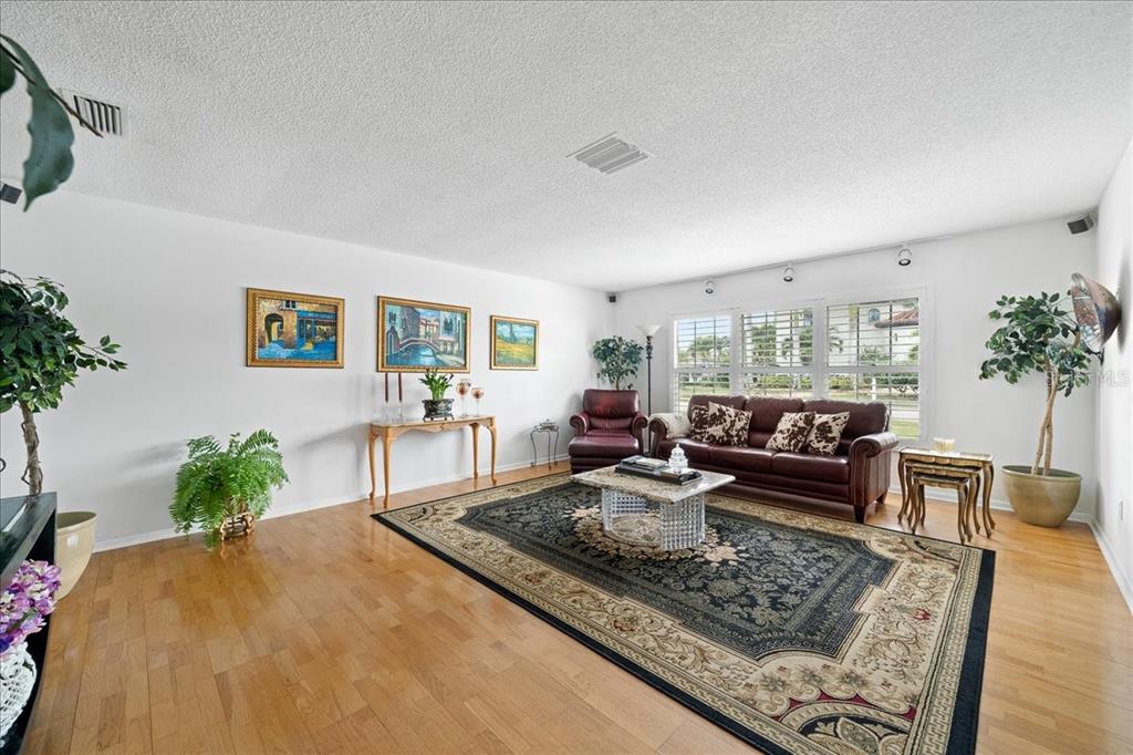 A living room features hardwood floors, a large area rug, and a brown leather sofa — 716 MALIBU LANE, INDIALANTIC, FL