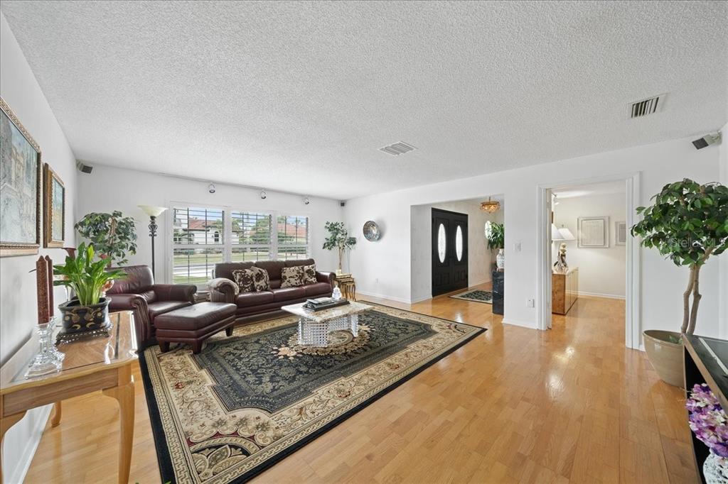 A living room with hardwood floors, a large area rug, and a dark leather sofa — 716 MALIBU LANE, INDIALANTIC, FL