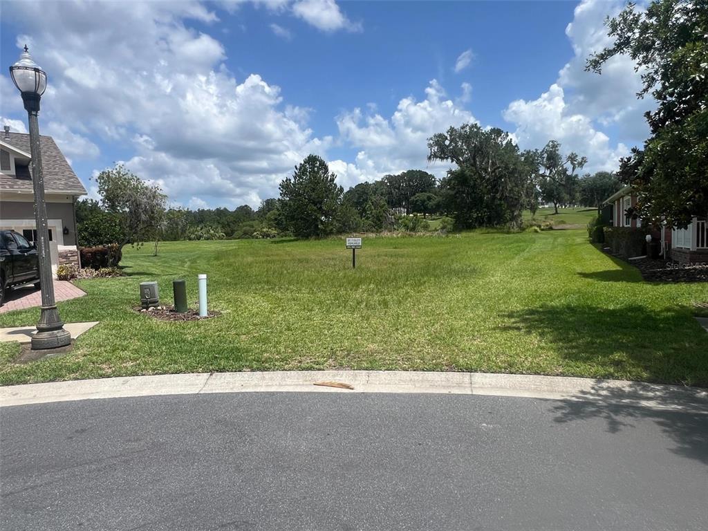 A vacant grassy lot sits between two houses on a sunny day — 19492 FOREST GARDEN COURT, BROOKSVILLE, FL