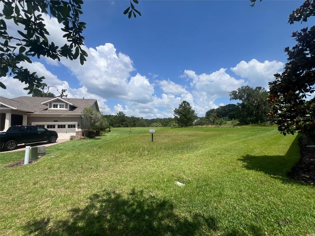 A grassy vacant lot sits next to a house with a garage and driveway — 19492 FOREST GARDEN COURT, BROOKSVILLE, FL