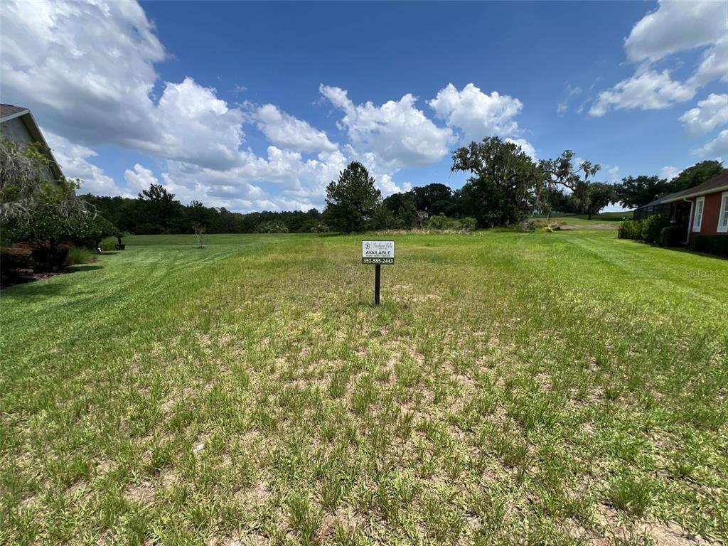 A vacant, grassy residential lot features a real estate sign in the center — 19492 FOREST GARDEN COURT, BROOKSVILLE, FL