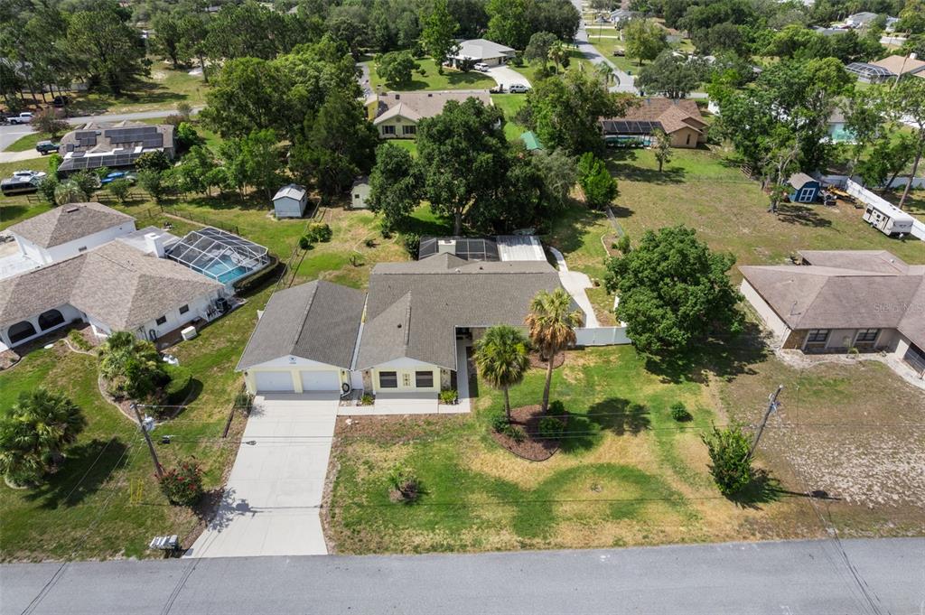 An aerial view shows a single-story house with a two-car garage and a backyard pool — 12380 TROUT CIRCLE, SPRING HILL, FL