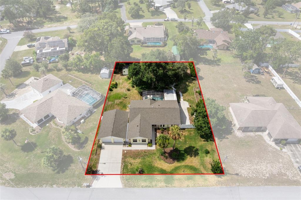 An aerial view shows a single-story house with a pool and a large yard — 12380 TROUT CIRCLE, SPRING HILL, FL