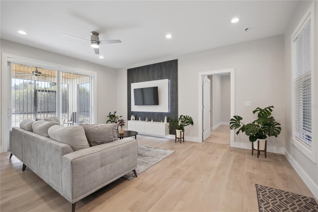 A living room features light wood floors, a gray sofa, and a wall-mounted television — 3031 BELLEFONTE AVENUE, NORTH PORT, FL