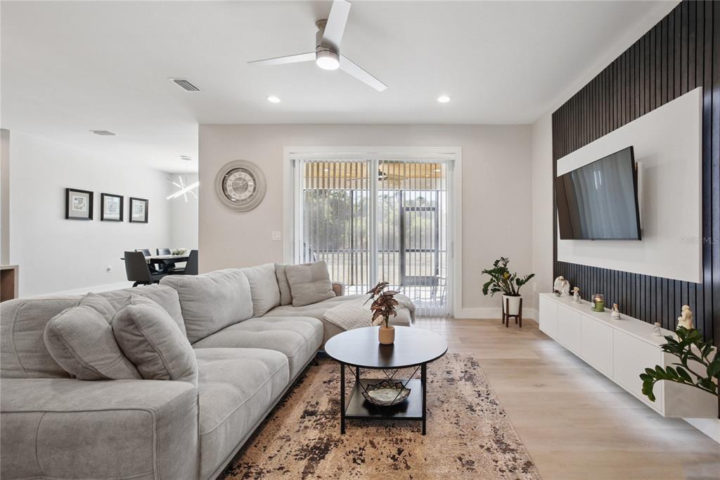 A living room features a grey sectional sofa, a round coffee table, and a wall-mounted television — 3031 BELLEFONTE AVENUE, NORTH PORT, FL