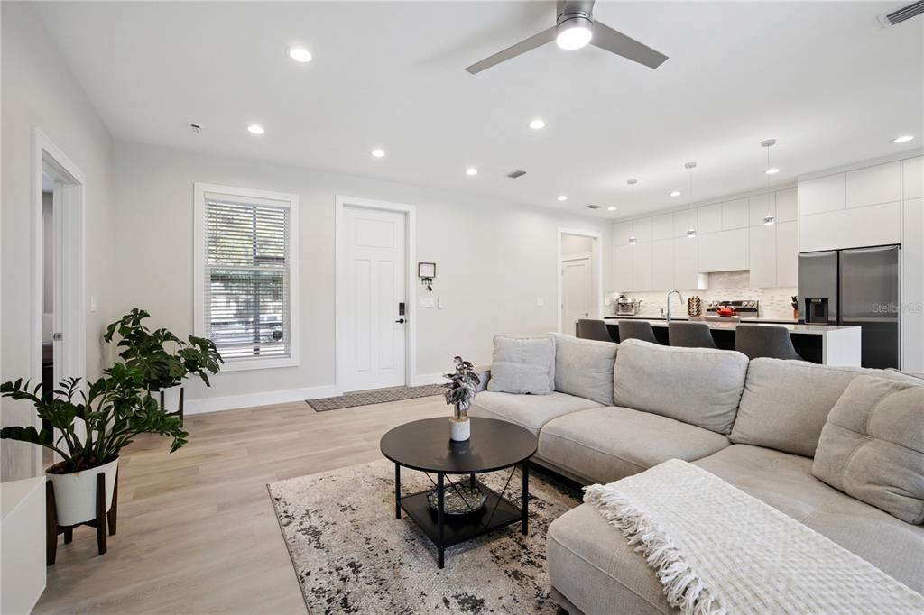 An open-concept living room features a sectional sofa, a coffee table, and a modern kitchen — 3031 BELLEFONTE AVENUE, NORTH PORT, FL