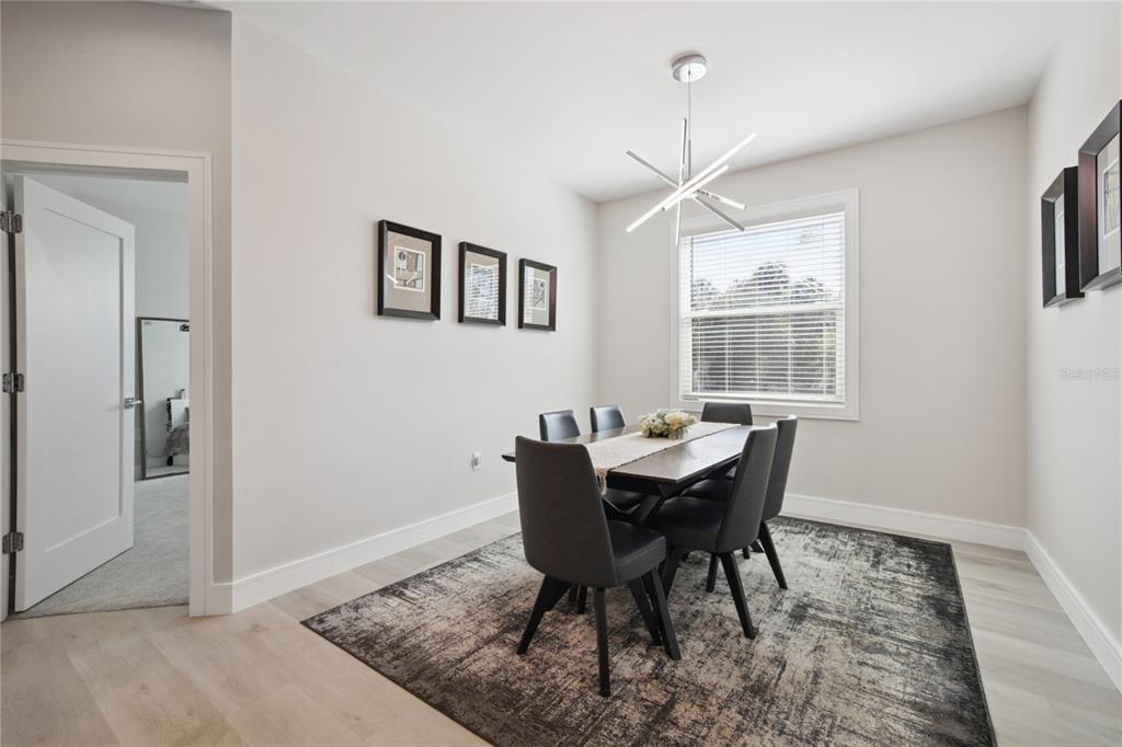 A dining room features a dark wood table, six grey chairs, and a modern chandelier — 3031 BELLEFONTE AVENUE, NORTH PORT, FL