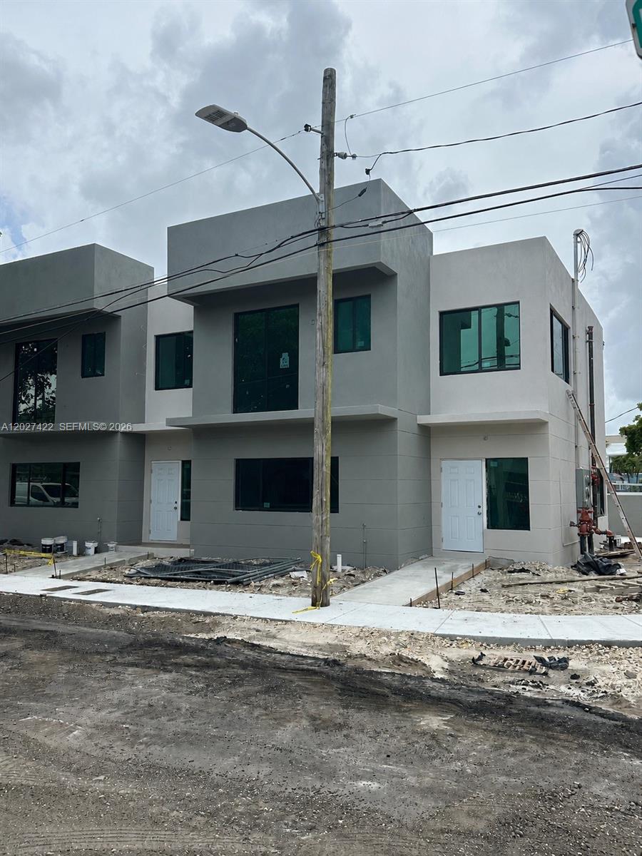 A modern two-story duplex exterior features gray stucco walls and white entry doors — 6480 NE 1st Ave, Miami FL 33150, MIAMI, FL