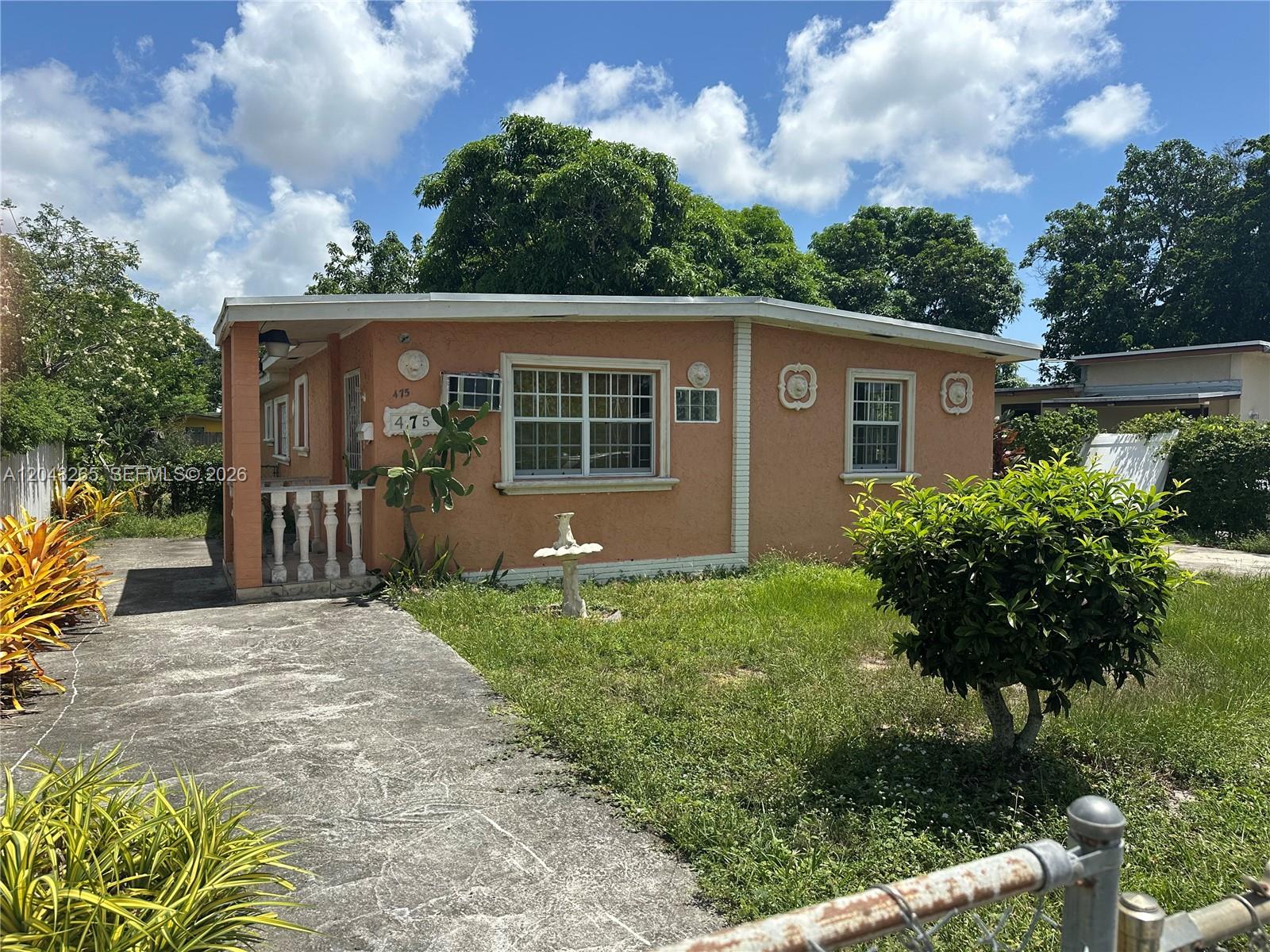 A single-story peach-colored house with a concrete driveway and a small front lawn — NORTH MIAMI, FL