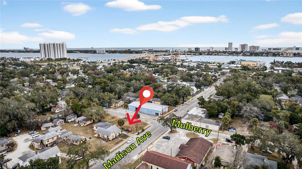 An aerial view shows a vacant lot marked with a pin near a street intersection — MADISON AVENUE, DAYTONA BEACH, FL