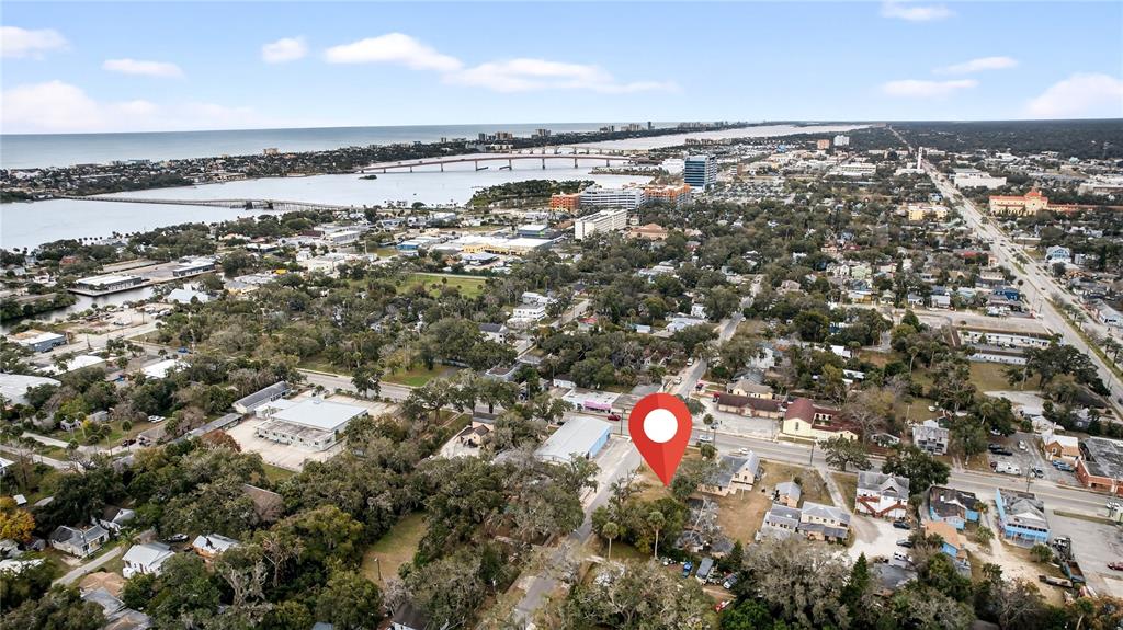 An aerial view shows a red location pin marking a vacant lot in a city — MADISON AVENUE, DAYTONA BEACH, FL
