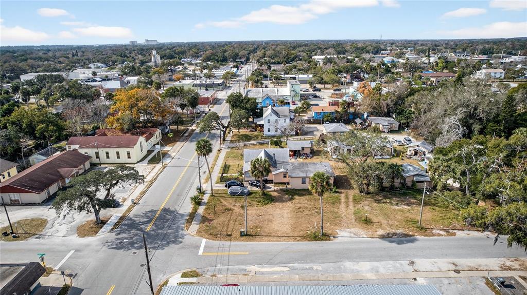 An aerial view shows a street intersection with several houses, trees, and vacant lots — MADISON AVENUE, DAYTONA BEACH, FL