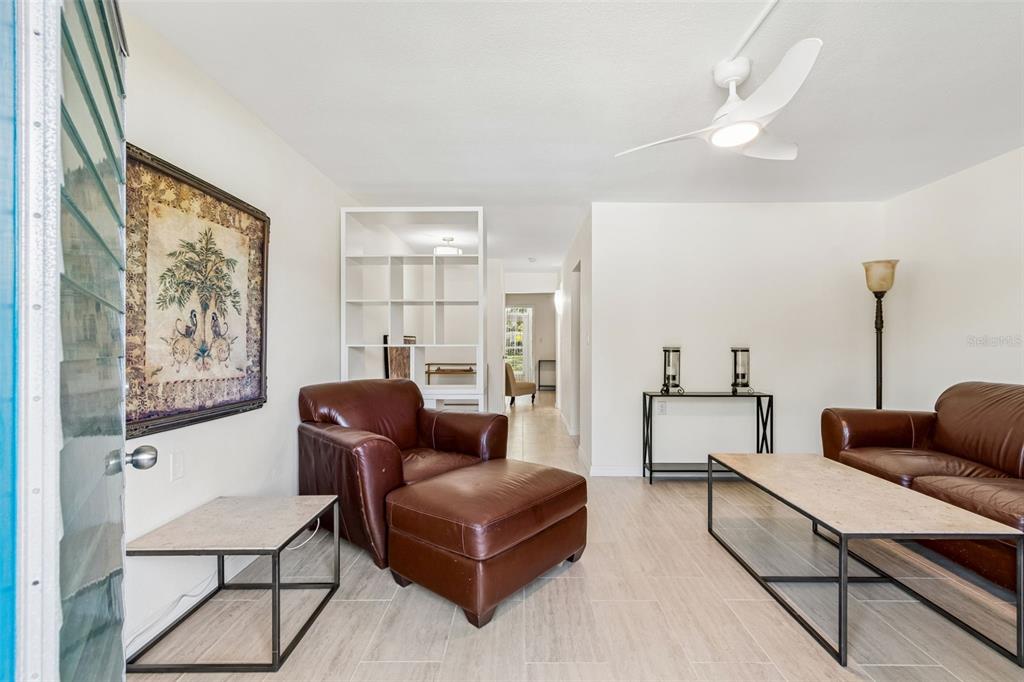 A living room features tile floors, leather furniture, a white ceiling fan, and open shelving — 8220 112TH STREET UNIT 106, SEMINOLE, FL