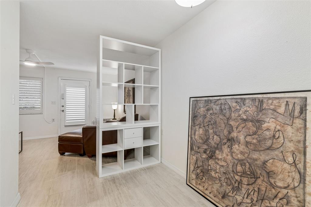 A white room features a modern open shelving unit as a divider and a large painting — 8220 112TH STREET UNIT 106, SEMINOLE, FL