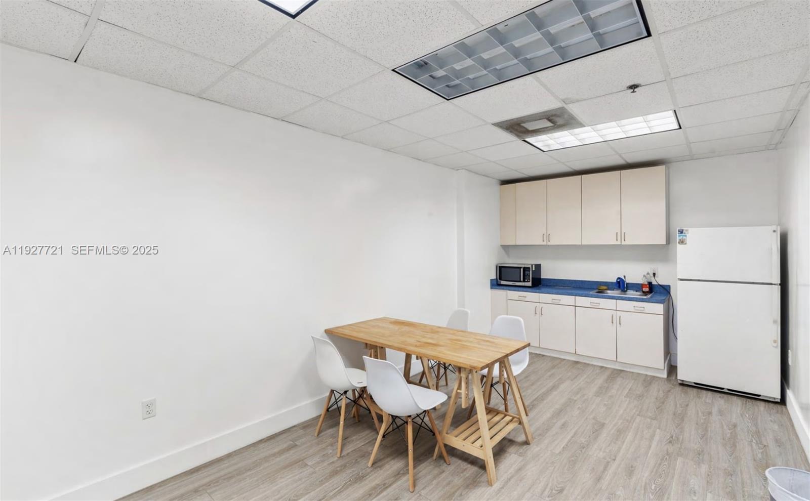 A breakroom features a wooden table with four chairs, white cabinets, and a refrigerator — 66 W FLAGLER ST # 502, Miami FL 33130, MIAMI, FL
