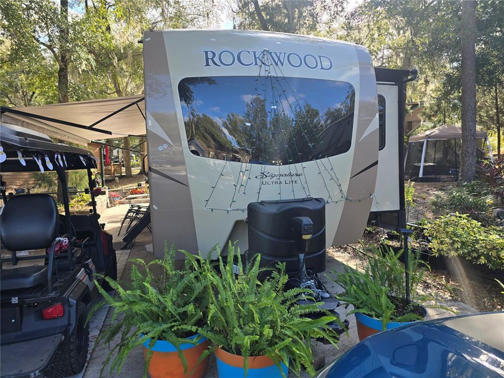 A Rockwood Signature Ultra Lite travel trailer is parked outdoors next to a golf cart — 25244 NE 143RD  ST UNIT 180, SALT SPRINGS, FL