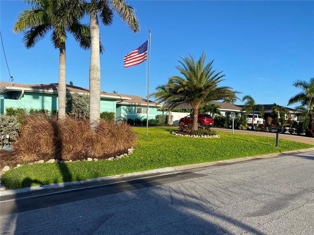 A teal house with a front lawn, palm trees, and an American flag on a pole — 3708 ROYAL PALM DRIVE, BRADENTON, FL