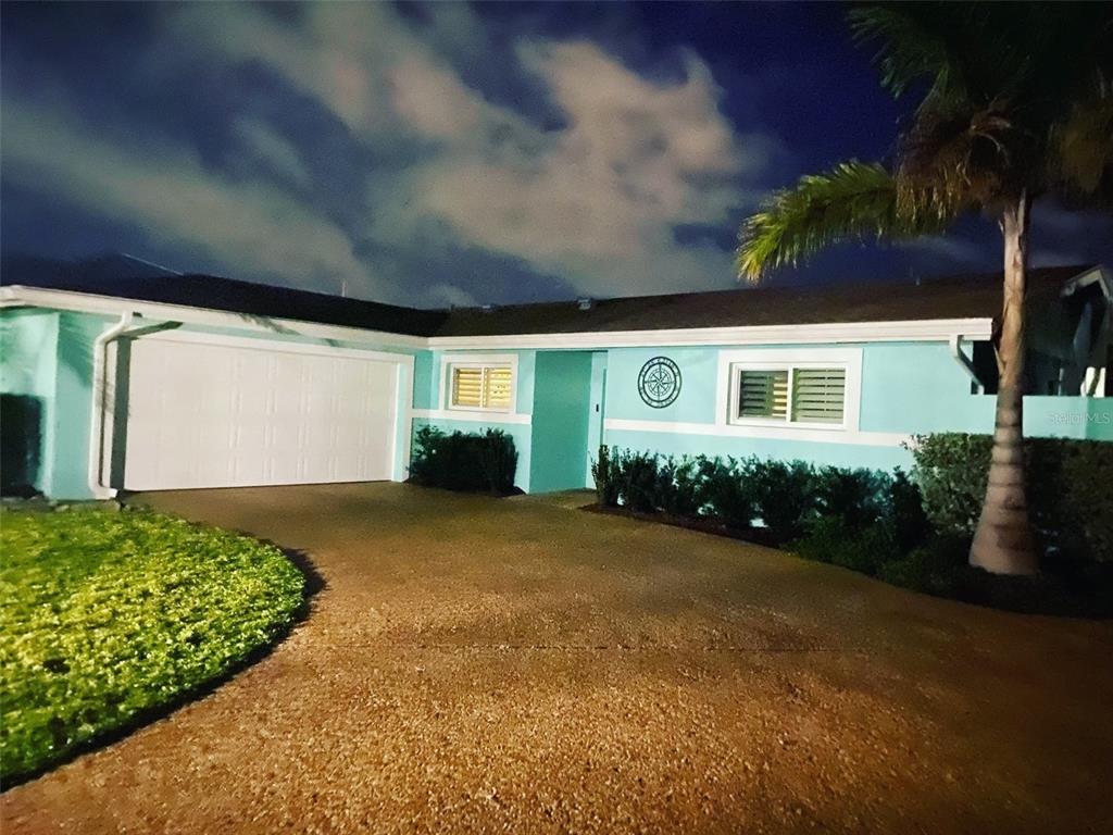 A teal, single-story house with a white garage door and a palm tree at night — 3708 ROYAL PALM DRIVE, BRADENTON, FL