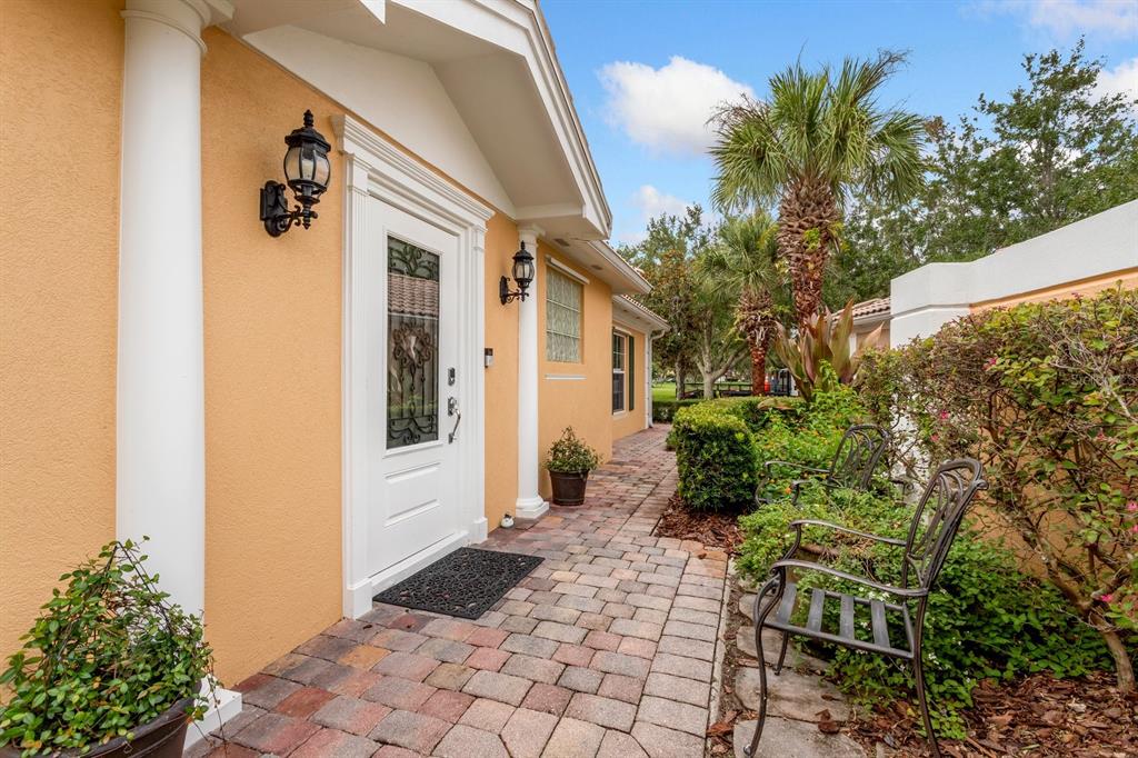 A paved walkway leads to a white front door framed by columns on a house — 11740 ASTILBE DRIVE, ORLANDO, FL