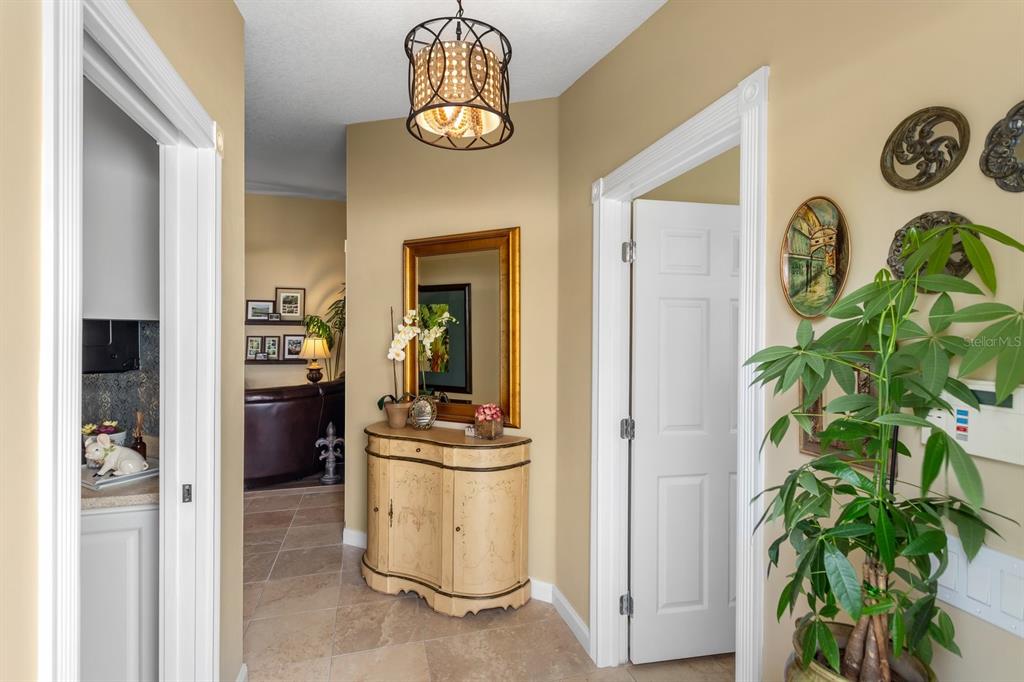 A hallway features tile flooring, a decorative light fixture, a console table, and a mirror — 11740 ASTILBE DRIVE, ORLANDO, FL