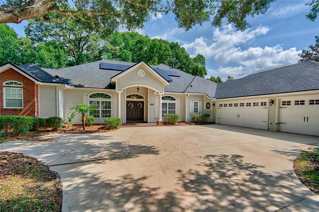 A single-story house with a brick accent, light siding, and a large concrete driveway — 9244 SW 31ST PLACE, GAINESVILLE, FL